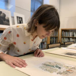 Image of IFPDA intern Jordan Hillman observing a colorful work on paper